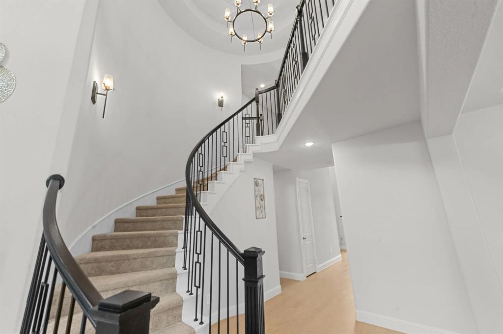 10969 Coastal Violet Road Frisco, TX 75035 - Photo 5 of 30 Staircase featuring a high ceiling, wood finished floors, and a chandelier