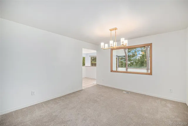 en empty room with windows and chandelier