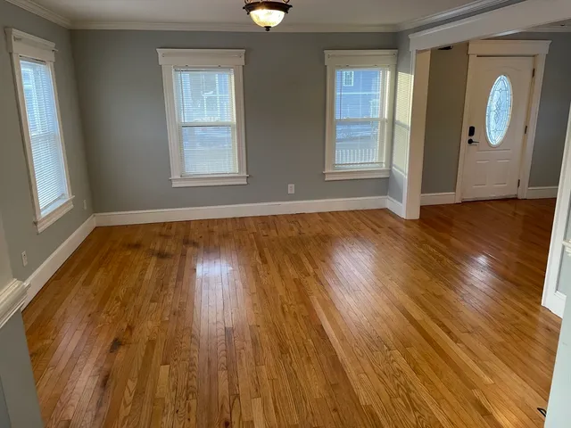 a view of an empty room with wooden floor and a window