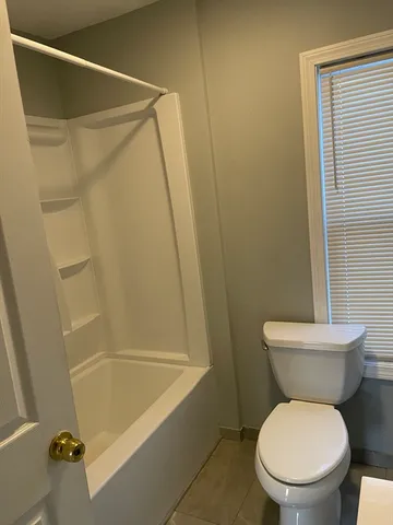 a white toilet sitting next to a bath tub