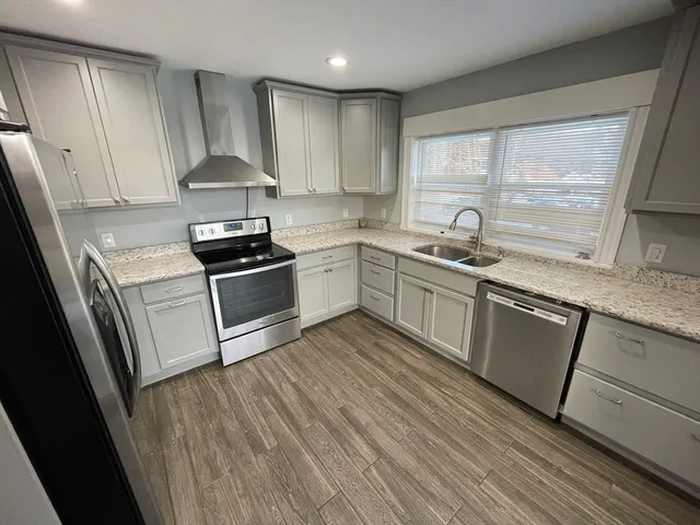 a kitchen with granite countertop a sink a stove and refrigerator