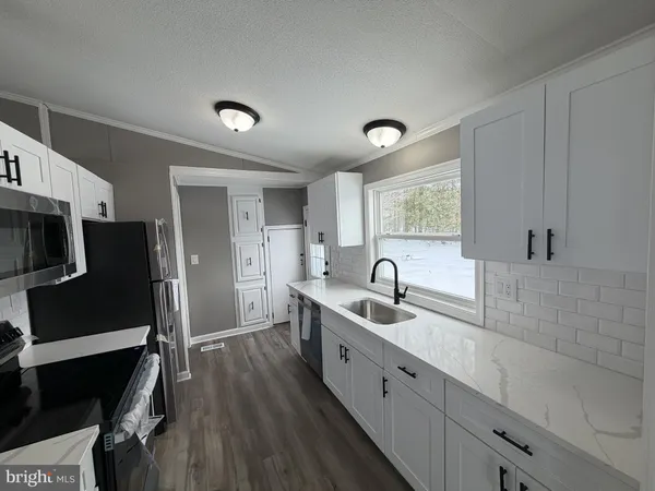 a kitchen with stainless steel appliances granite countertop a sink refrigerator and cabinets