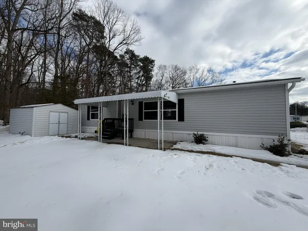 a front view of house with yard and trees in the background