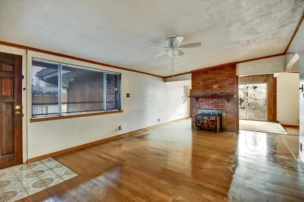 a view of an empty room with a window and kitchen view
