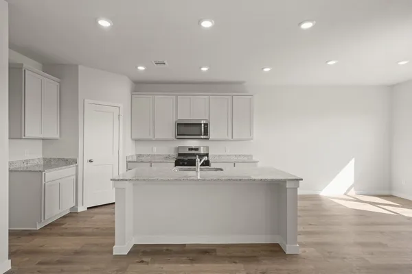 a large white kitchen with kitchen island a sink a stove a refrigerator and white cabinets
