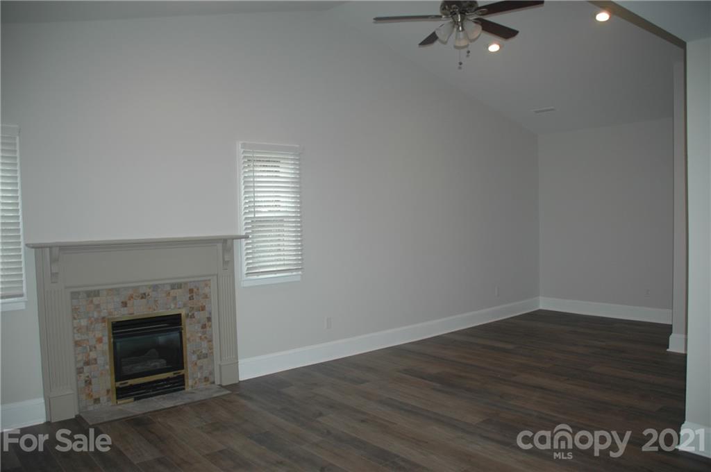 521 Gray Drive Charlotte, NC 28213 - Photo 21 of 34 an empty room with wooden floor a fireplace and windows