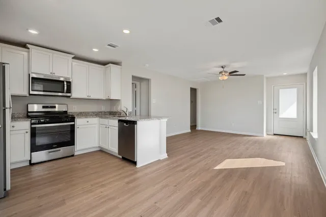 a kitchen with granite countertop white cabinets and stainless steel appliances