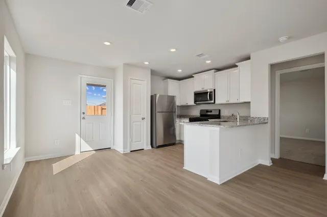 a kitchen with stainless steel appliances granite countertop a refrigerator oven a stove top oven a sink and dishwasher with wooden floor