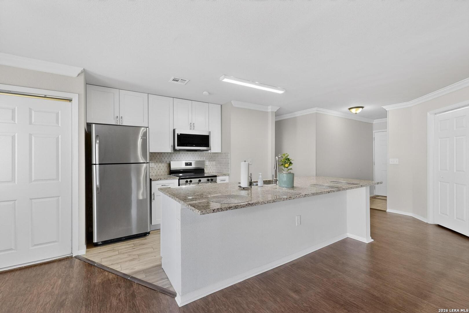 7219 Spring Drops Street San Antonio, TX 78249 - Photo 11 of 37 a kitchen with stainless steel appliances granite countertop a refrigerator a stove a microwave and white cabinets