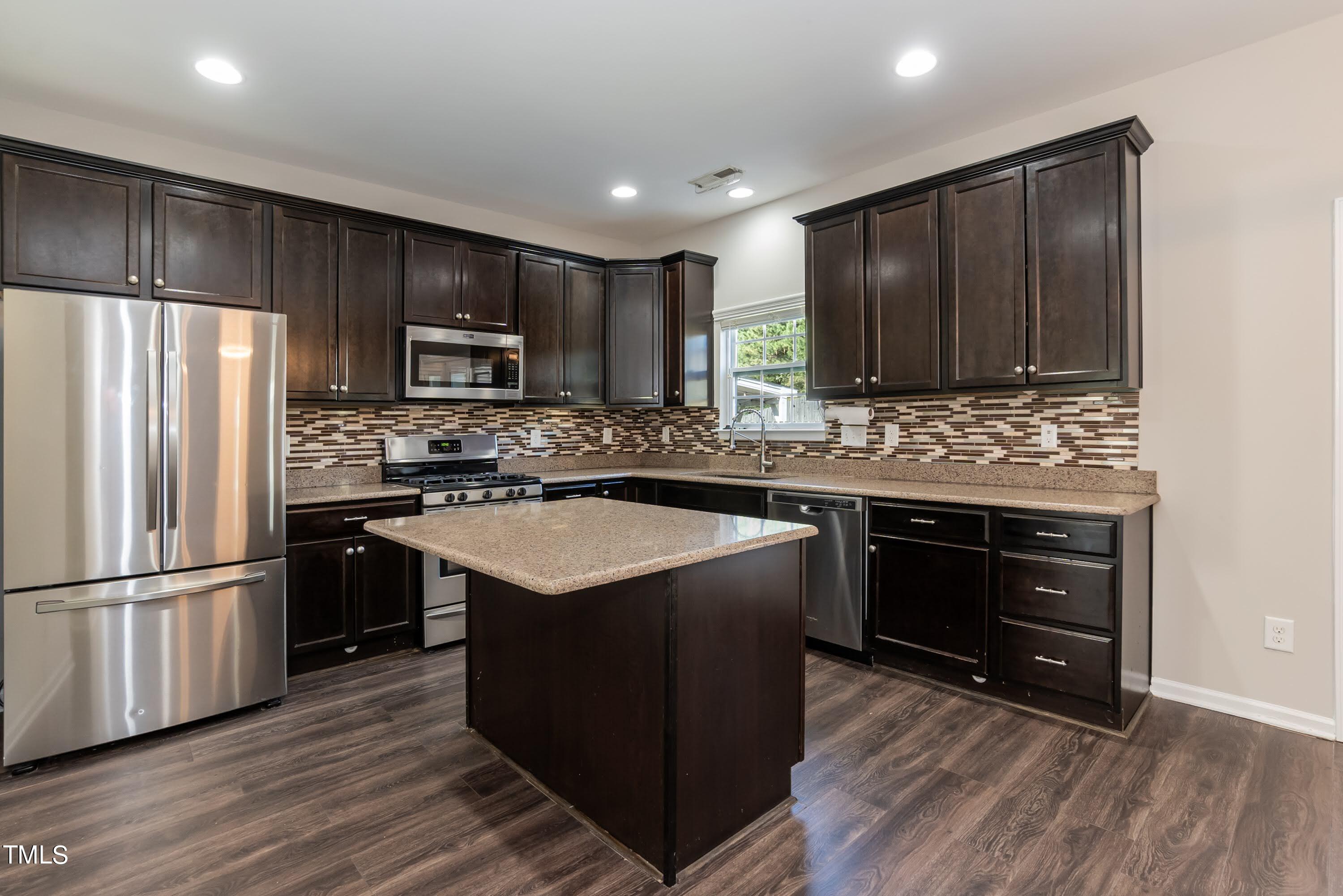 408 Cottesbrook Drive Wake Forest, NC 27587 - Photo 7 of 37 a kitchen with kitchen island granite countertop wooden cabinets a refrigerator and a stove top oven