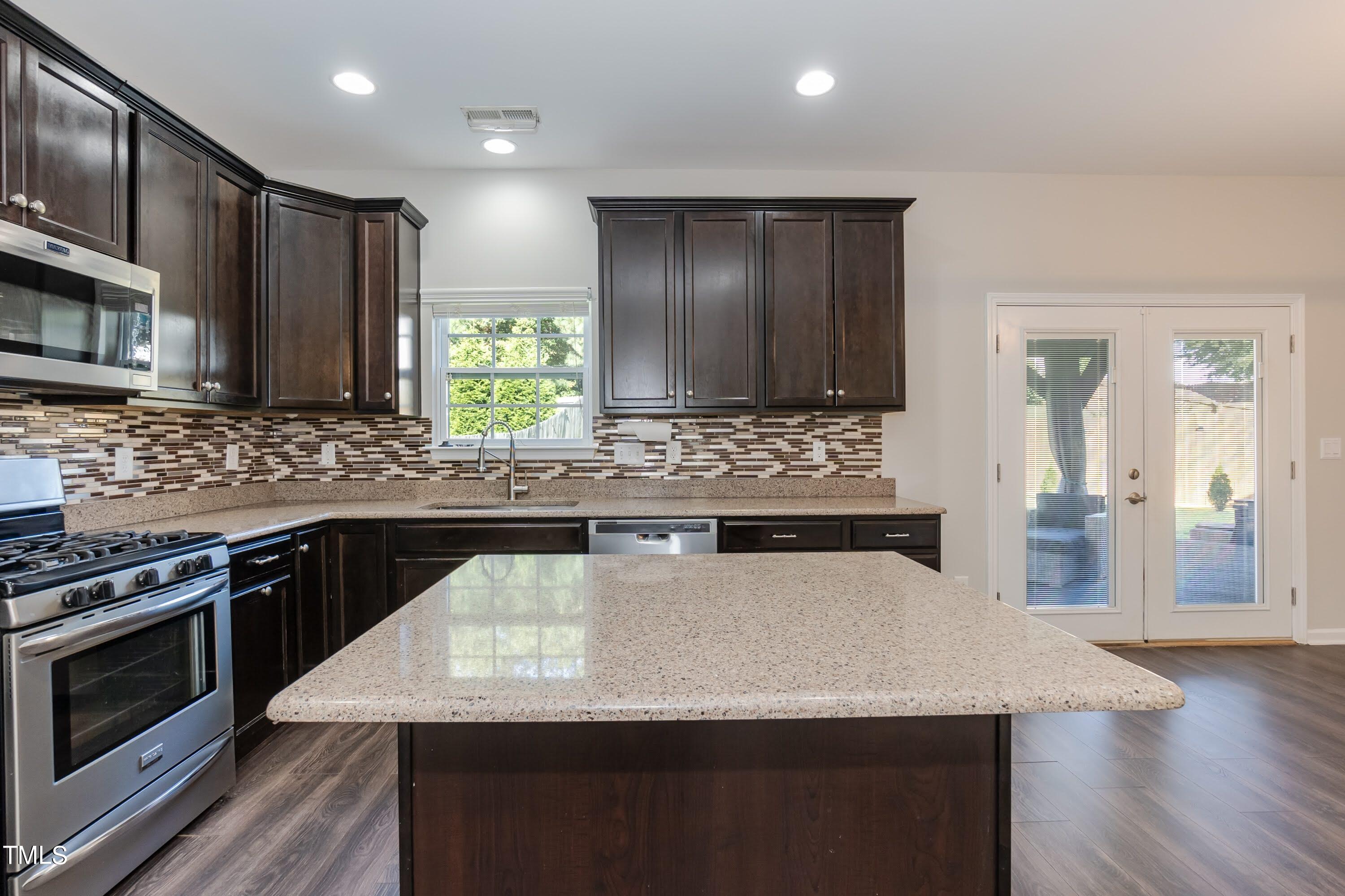 408 Cottesbrook Drive Wake Forest, NC 27587 - Photo 8 of 37 a kitchen with stainless steel appliances kitchen island granite countertop a stove a sink and a microwave