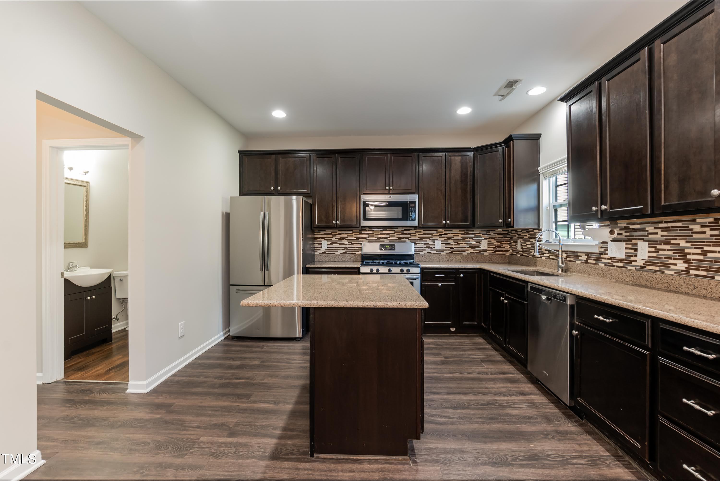 408 Cottesbrook Drive Wake Forest, NC 27587 - Photo 9 of 37 a kitchen with kitchen island granite countertop wooden cabinets a refrigerator and a sink