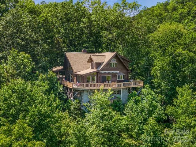 an aerial view of a house with yard and trees in the background