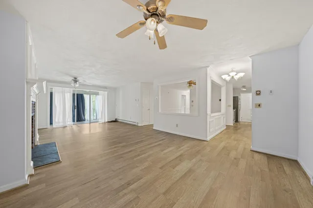 a view of a livingroom with wooden floor a ceiling fan and windows