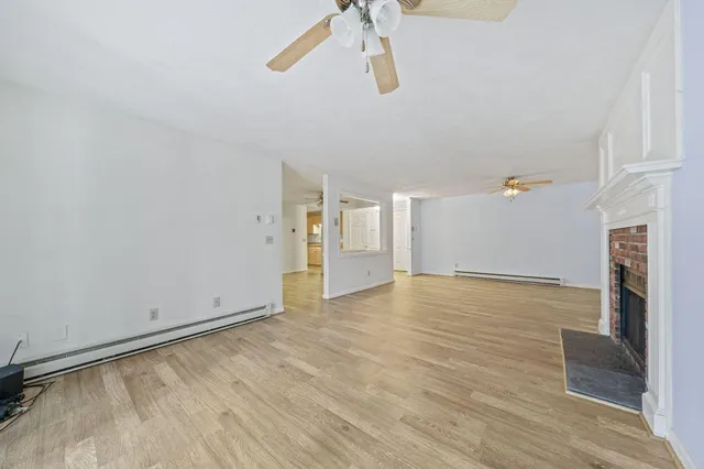 a view of empty room with wooden floor and fireplace