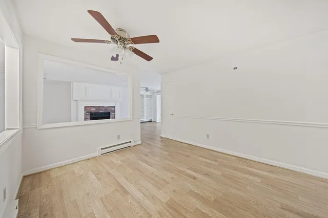 a view of empty room with wooden floor and ceiling fan