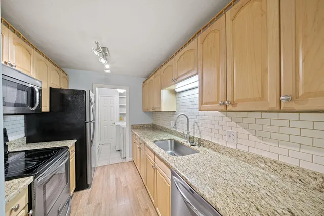 a kitchen with granite countertop a sink a counter space appliances and cabinets