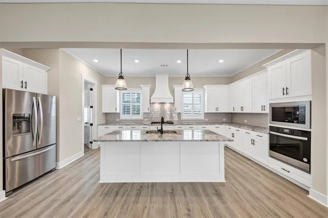 a large kitchen with cabinets wooden floor and stainless steel appliances