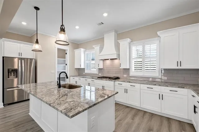 a kitchen with stainless steel appliances granite countertop a sink a stove a refrigerator and island with wooden floor