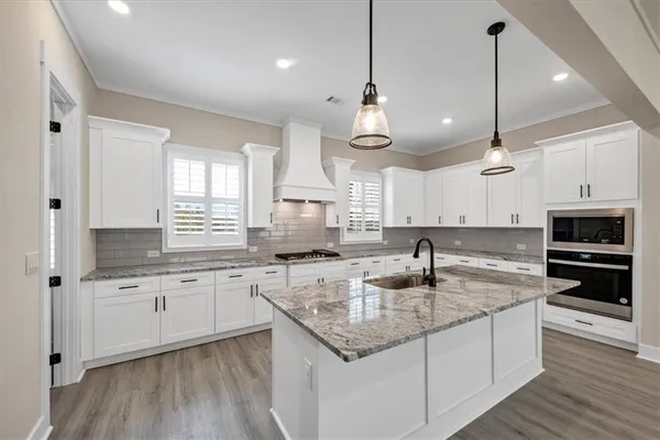 a kitchen with stainless steel appliances granite countertop a sink a stove and oven with wooden floor