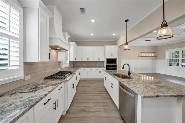 a kitchen with granite countertop stainless steel appliances a sink stove and cabinets