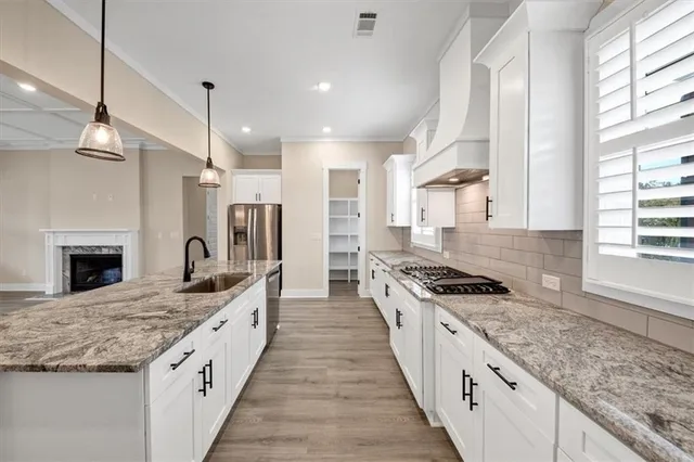 a large kitchen with granite countertop a stove top oven a sink a counter space and stainless steel appliances