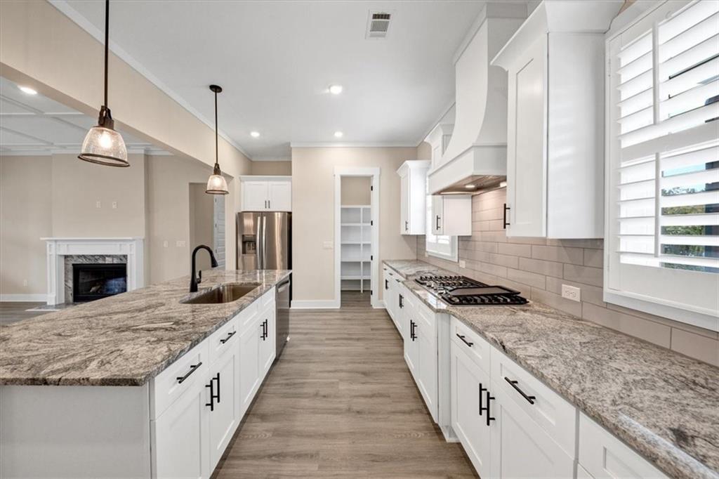 354 Oxford Road Ball Ground, GA 30107 - Photo 16 of 48 a large kitchen with granite countertop a stove top oven a sink a counter space and stainless steel appliances