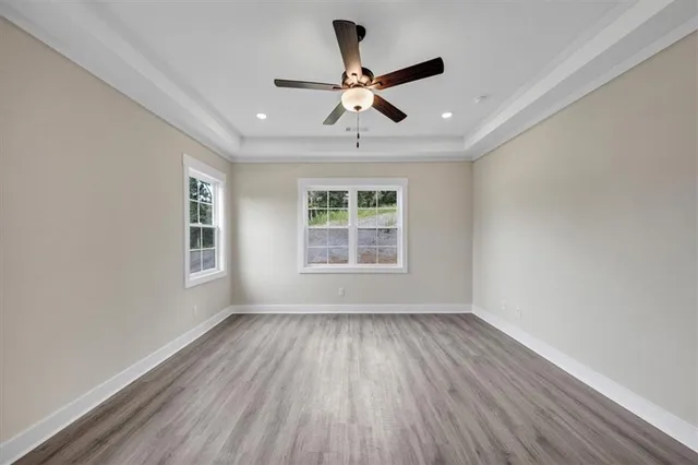 a view of empty room with wooden floor and fan