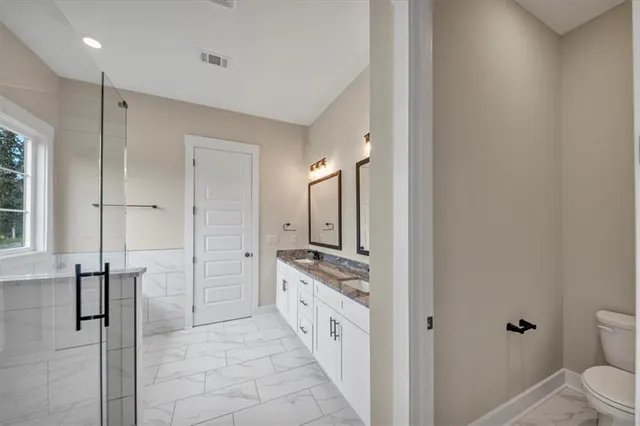 a bathroom with a granite countertop sink a toilet and shower
