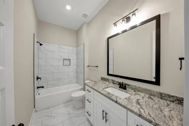 a bathroom with a granite countertop sink a toilet and bathtub