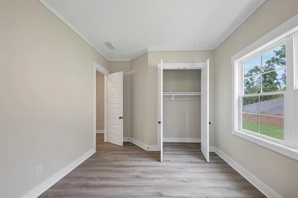 a view of an empty room with wooden floor and window