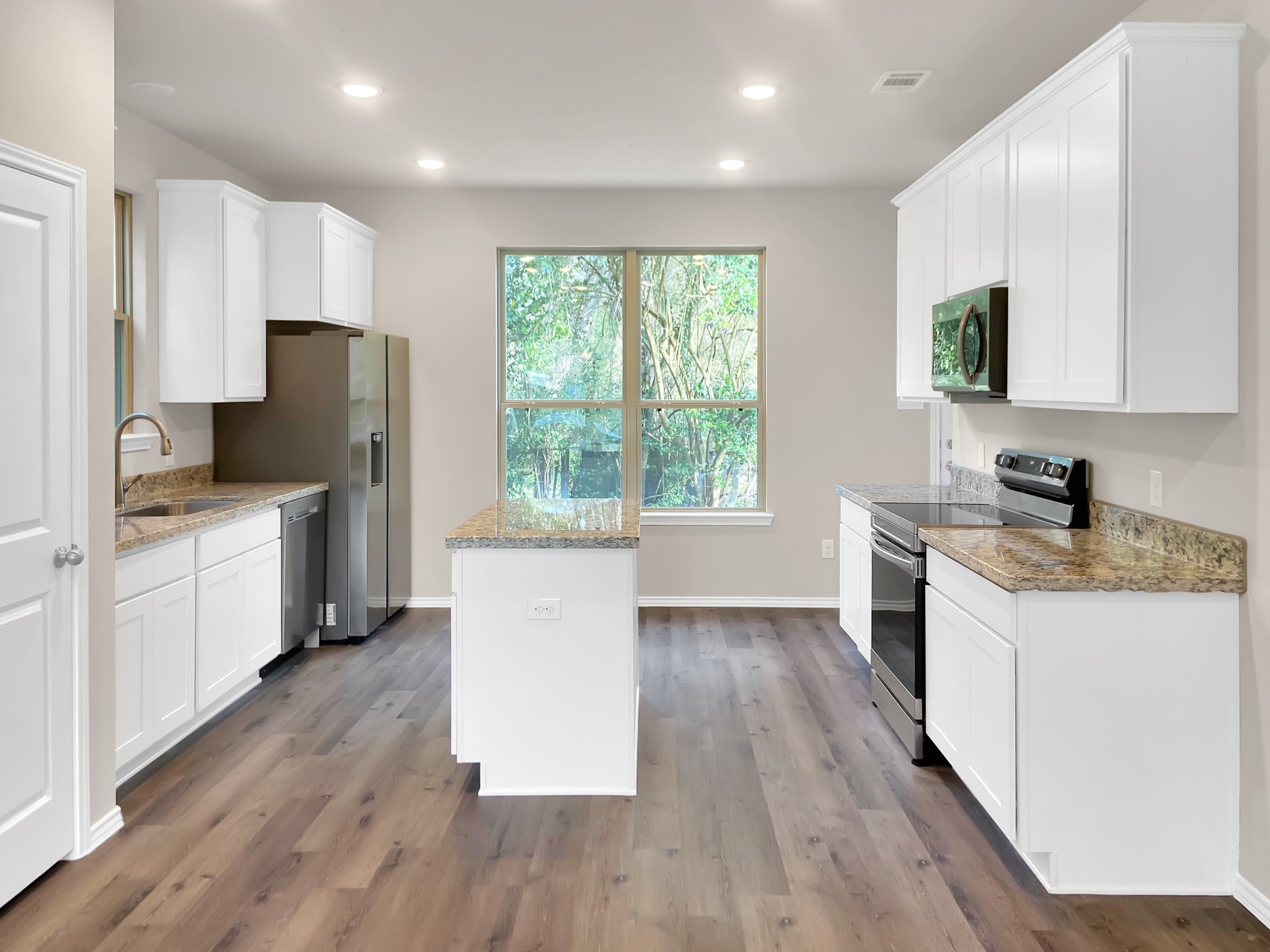 405 Mohawk Drive Conroe, TX 77316 - Photo 6 of 22 a kitchen with granite countertop a stove a sink a refrigerator and white cabinets with wooden floor