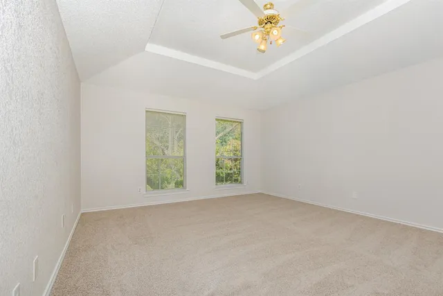 an empty room with windows and chandelier fan