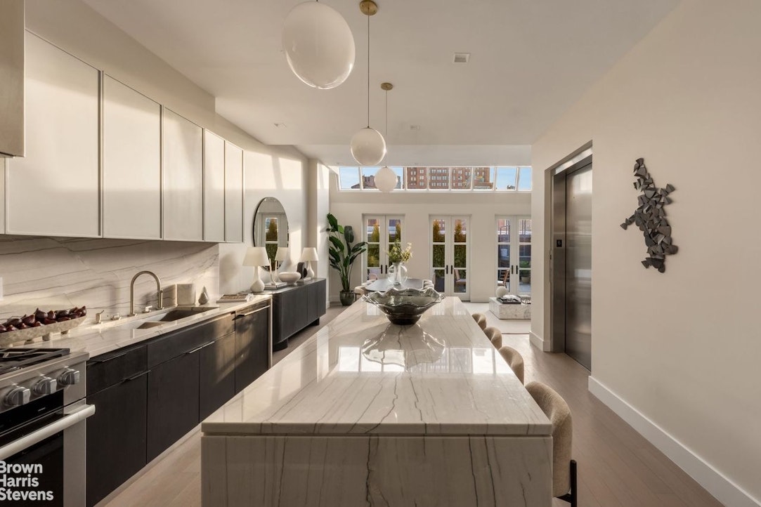 74 Grand Street, Unit PH Manhattan, NY 10013 - Photo 3 of 18 a kitchen with kitchen island granite countertop a stove a sink a refrigerator cabinets and wooden floor