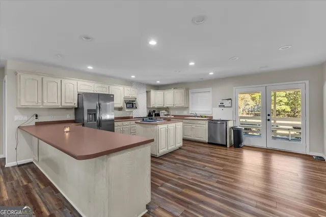 a kitchen with stainless steel appliances granite countertop wooden cabinets a sink a stove a refrigerator and white cabinets