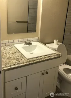 a bathroom with a granite countertop sink a toilet and mirror