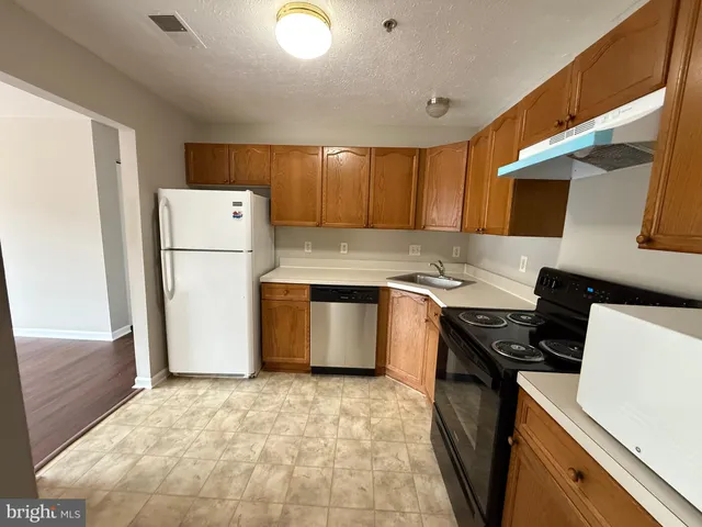 a kitchen with a refrigerator a stove top oven a sink and cabinets