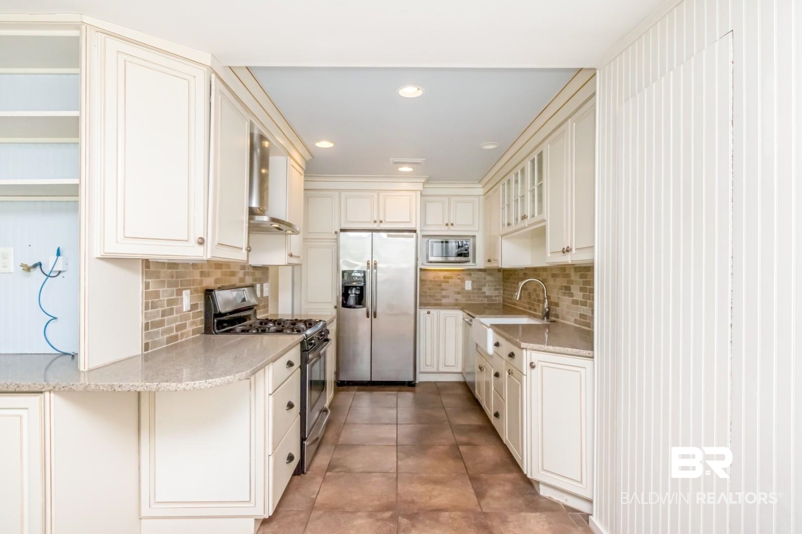 10 South Hathaway Road Mobile, AL 36608 - Photo 11 of 46 Kitchen with appliances with stainless steel finishes, glass insert cabinets, light stone counters, wall chimney range hood, and recessed lighting
