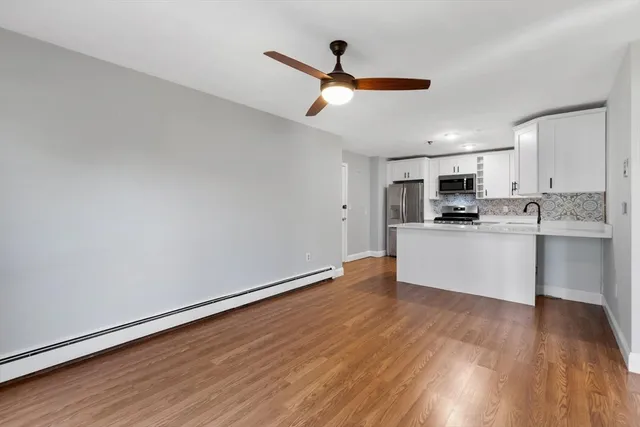 a living room with stainless steel appliances kitchen island granite countertop a wooden floors