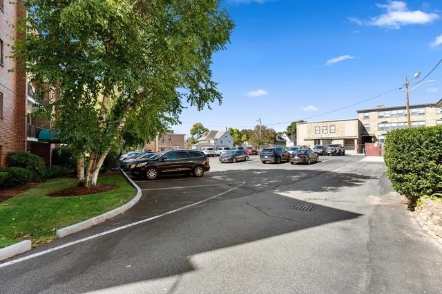 a view of road with card parked on side and retail shops