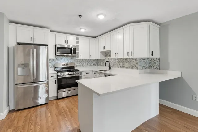 a kitchen with kitchen island white cabinets and stainless steel appliances