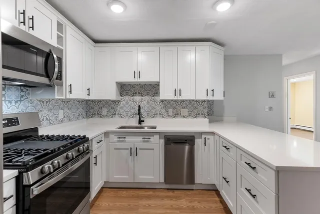 a kitchen with stainless steel appliances granite countertop a sink stove oven and white cabinets