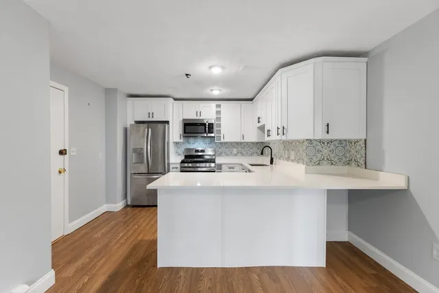 a kitchen with kitchen island white cabinets and stainless steel appliances