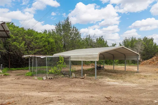 a backyard of a house with table and chairs under an umbrella