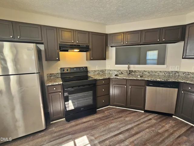 a kitchen with stainless steel appliances granite countertop a sink stove and refrigerator