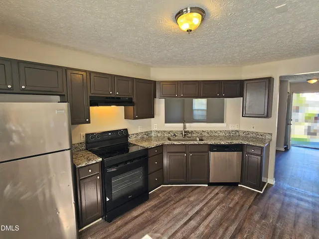 a kitchen with granite countertop a refrigerator stove and microwave
