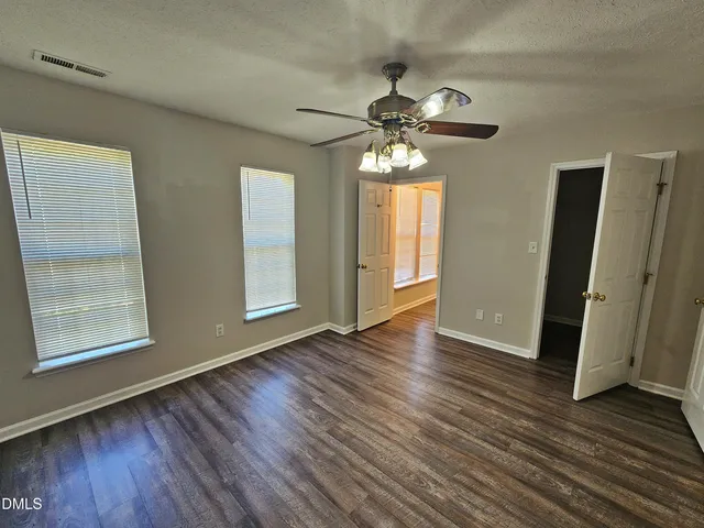 a view of an empty room with wooden floor and window