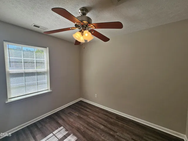 an empty room with a window and a fan