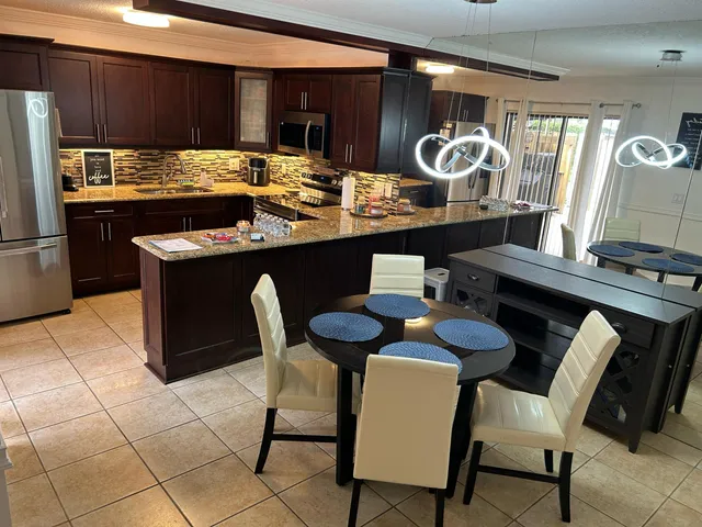 a kitchen with granite countertop a table chairs stove and refrigerator