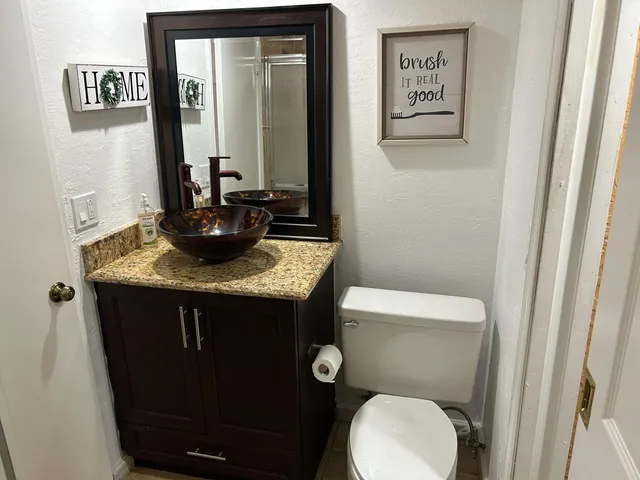 a bathroom with a granite countertop toilet sink and mirror